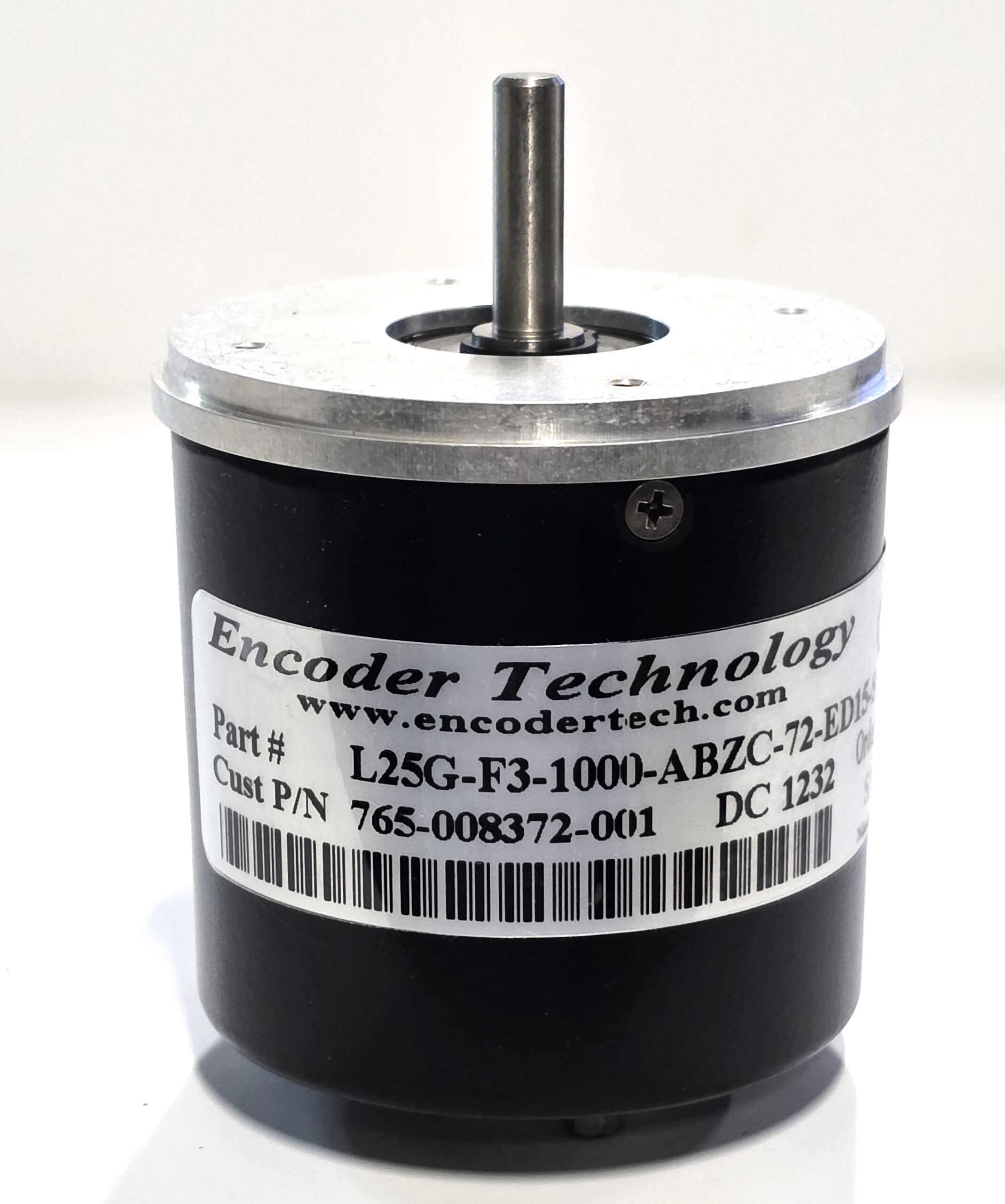 Close-up of a black encoder housing with a vertical metal shaft and a barcode-label wrap. It appears to be a position-sensing device used in machinery.