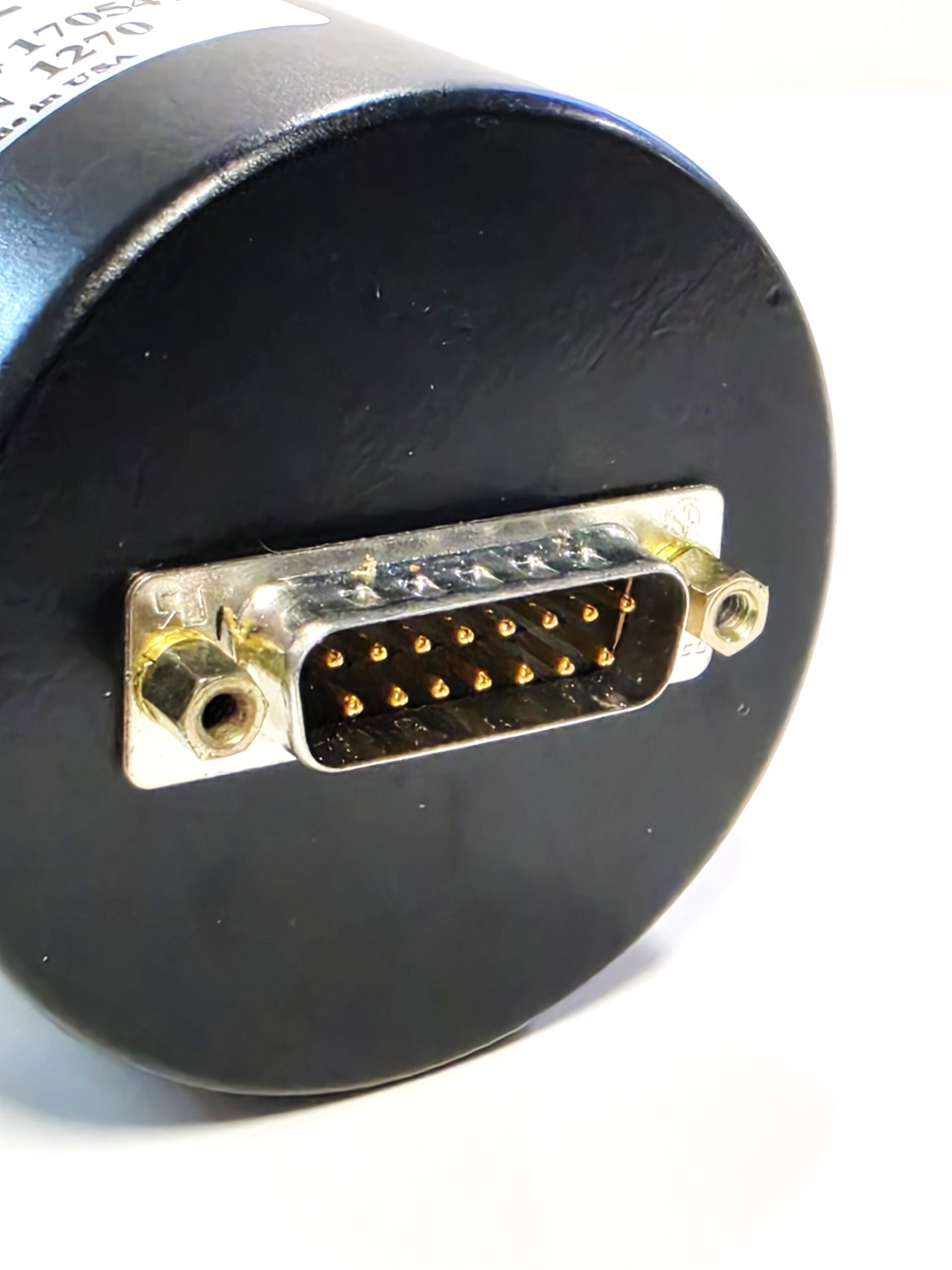 Close-up of a round black electronic device with a metal 26-pin D-sub connector and two mounting screws on the sides.