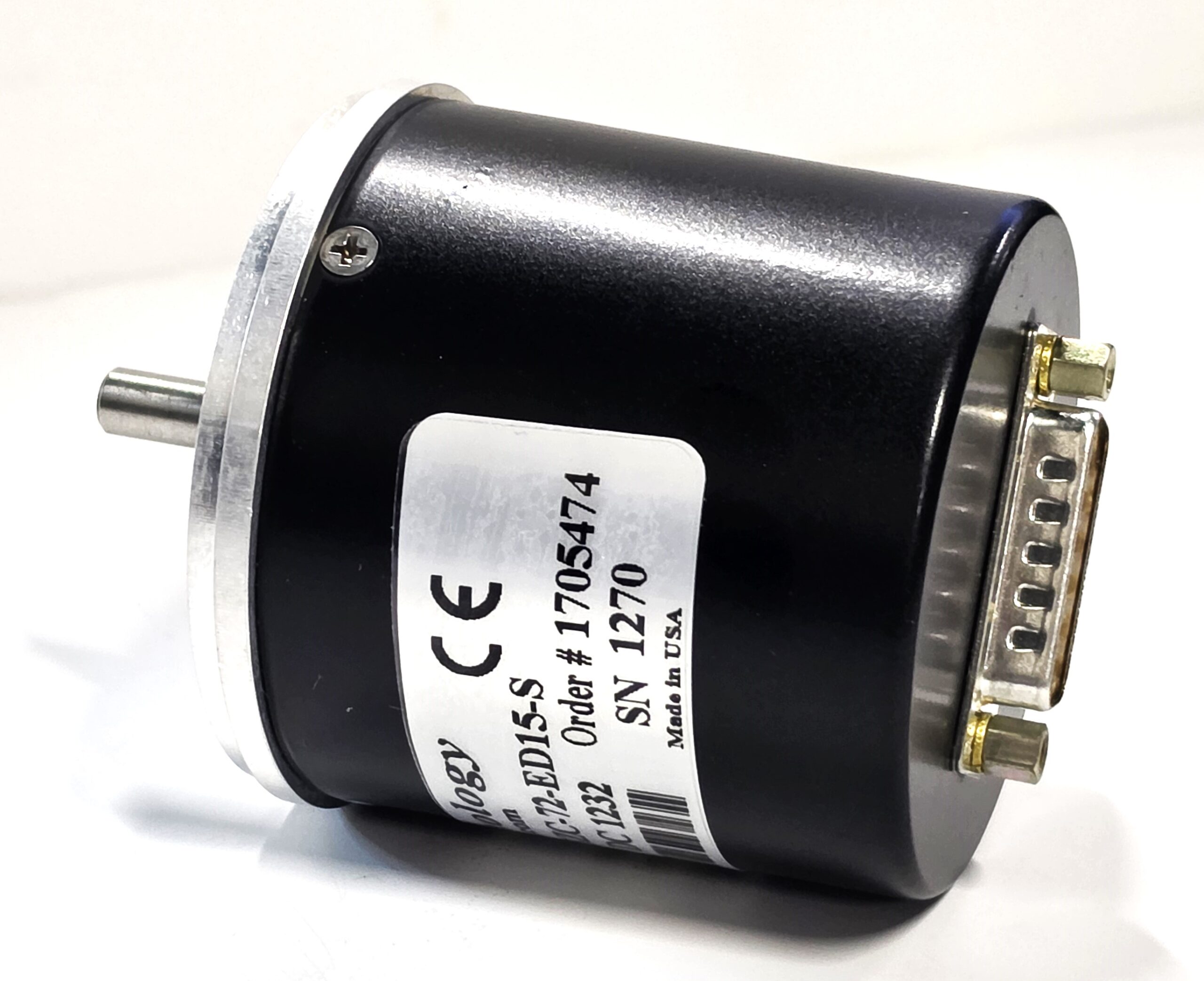 Close-up of a small cylindrical DC motor with a metal shaft on the left, mounting flange, and a white label on the body.