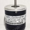 Close-up of an encoder with a metal shaft protruding from a black cylindrical housing and a barcode label nearby on the side of the device.