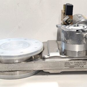 Close-up of a stainless steel industrial machine with a circular dial and a small valve/connector on a metal base; serial number plate visible on the side.