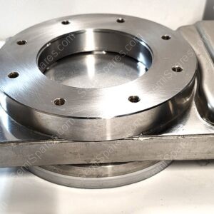 Close-up of a brushed stainless steel flange with a large central bore and several small threaded holes around the edge, mounted to a metal housing.