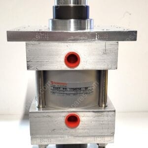 Close-up of a stainless-steel pneumatic actuator mounted on a square metal base, showing a silver cylindrical piston, black mid-section, and red circular ports on the side with a label on the body.