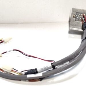 Close-up of a multi-wire electrical harness connected to a perforated metal connector plate.
