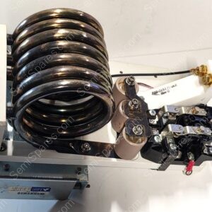 Close-up of a large black metal coil spring assembly mounted to a white frame, with electrical terminals and wiring nearby.