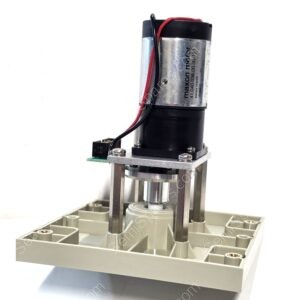 Close-up of a small electric motor mounted to a metal frame with red and black wires, attached to a gray base plate.