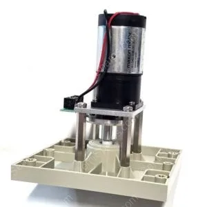 Close-up of a small electric motor mounted to a metal frame with red and black wires, attached to a gray base plate.