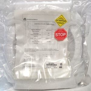 Clear plastic bag containing an Applied Materials certificate of compliance with yellow ATTENTION and red STOP stickers visible.