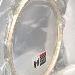 Close-up of a metallic circular hoop inside shiny protective foil packaging with a warning label visible on the container.