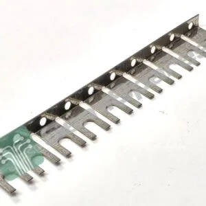 Metal gauge/ruler strip with multiple forked tines and circular holes, laid diagonally on a white background.