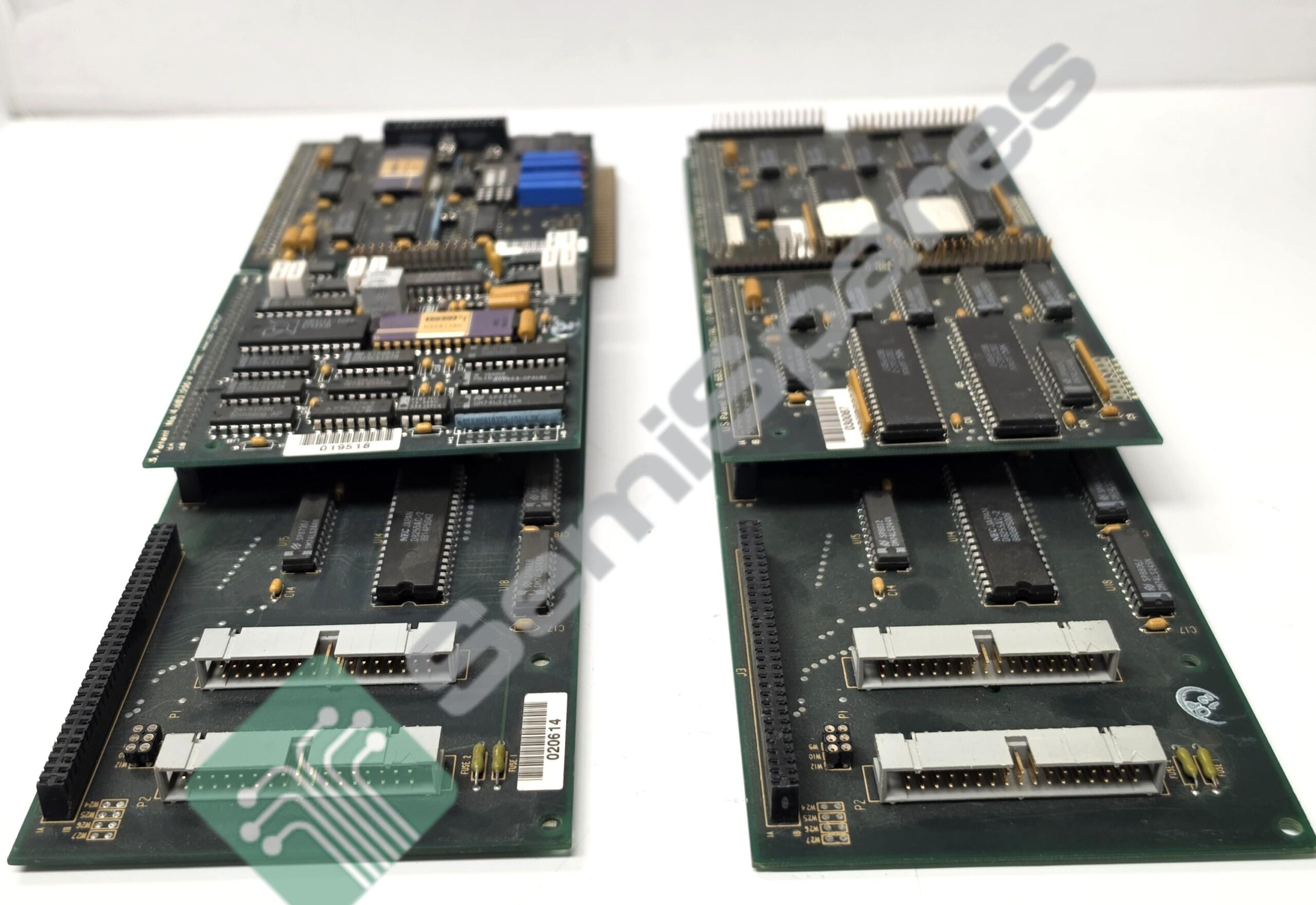 Two vintage circuit boards with numerous DIP chips and edge connectors laid on a white surface.