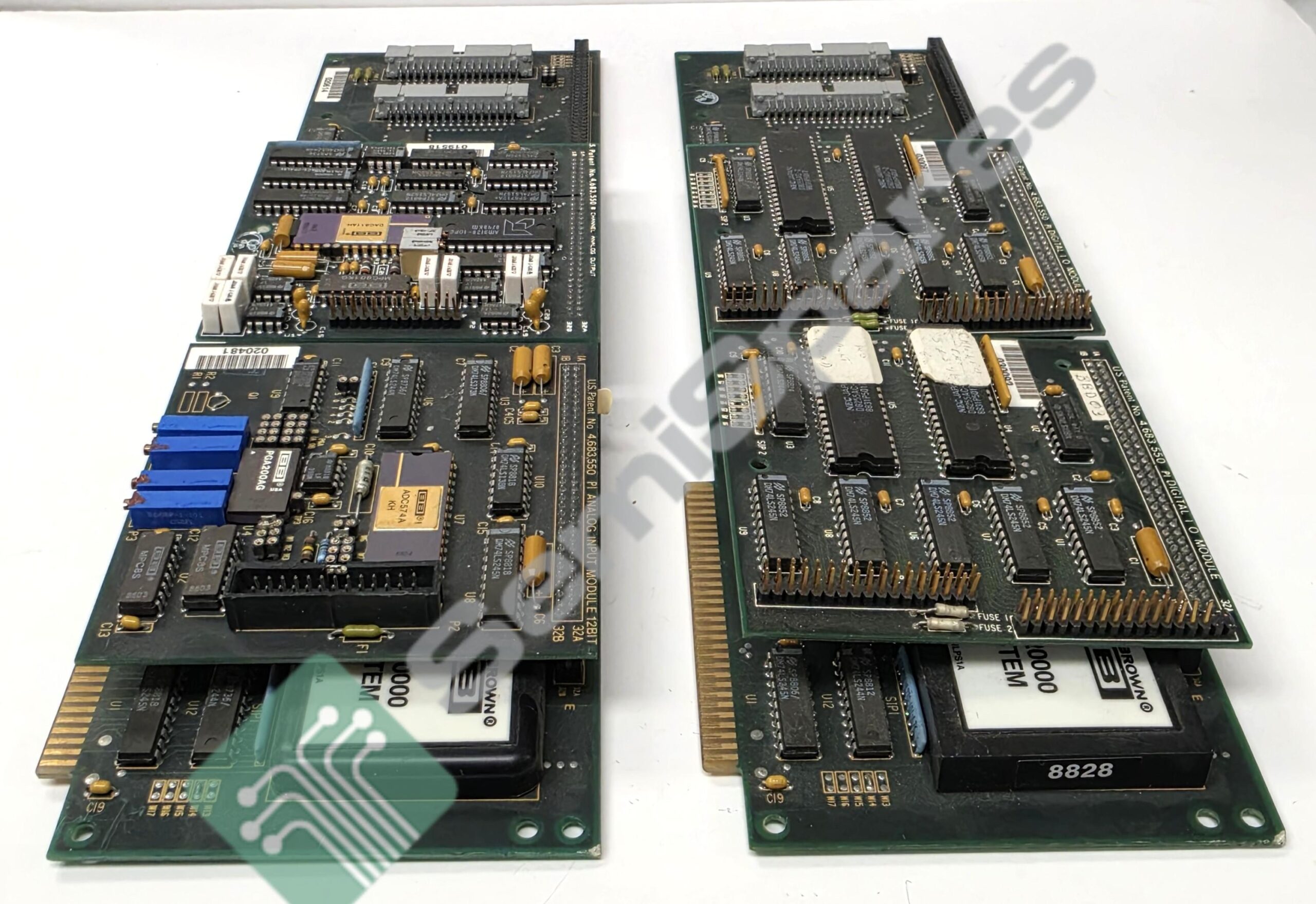 Two vintage green printed circuit boards laid side by side on a white surface, showing dense DIP chips, connectors, and blue plug components at one end.