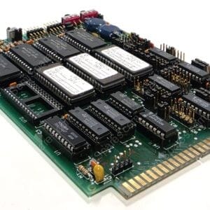 Green circuit board populated with many DIP integrated circuits and a gold edge connector on one side.