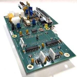 Close-up of a green circuit board with resistors, capacitors, blue connectors, and a large multi-pin edge connector on a white background.