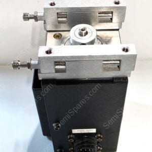 Close-up of a small metal linear positioning stage with threaded adjustment screws, mounted on a black base, and a central circular knob for alignment.