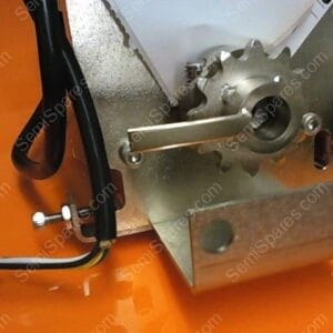 Metal cogwheel and mounting bracket attached to an orange surface, with a black cable and screws visible.