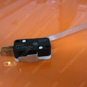 Small micro switch with a metal lever actuator on an orange surface, showing two fuse-like terminals.