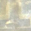 Blurred, weathered wall with pale beige rectangular patches and soft gray tones in a muted abstract texture.