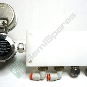 Close-up of a pneumatic pressure regulator with inlet and outlet fittings mounted to a white panel.