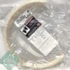 Beige circular gasket sealed in clear plastic with a white warning label and a green tag featuring a circuit design.