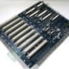 Blue motherboard PCB with multiple long beige PCI/ISA expansion slots and connectors lying on a white surface.