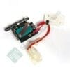 Wires and a small electronic module with red connectors and a green circuit board, partially mounted on metal hardware.