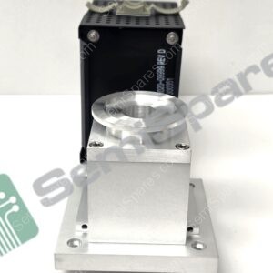 Close-up of a precision metal fixture: black perforated block with screws, and a cylindrical silver cup seated in a silver base plate, watermark visible in the background.