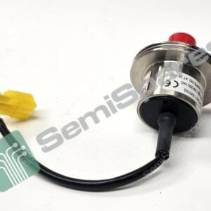 Close-up of a metallic cylindrical device with a red push button and black cables on a white surface; a yellow connector is visible on the left.